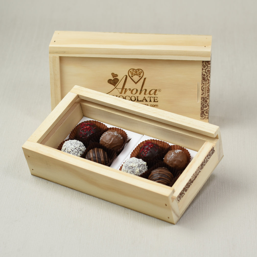 Aroha Chocolate Eight Mixed Truffles Luxury Wooden Gift Box, in front is an open box showing the beautiful hand rolled truffles a closed box with the Aroha Chocolate logo sits behind the open box highlighting the over all look when received.