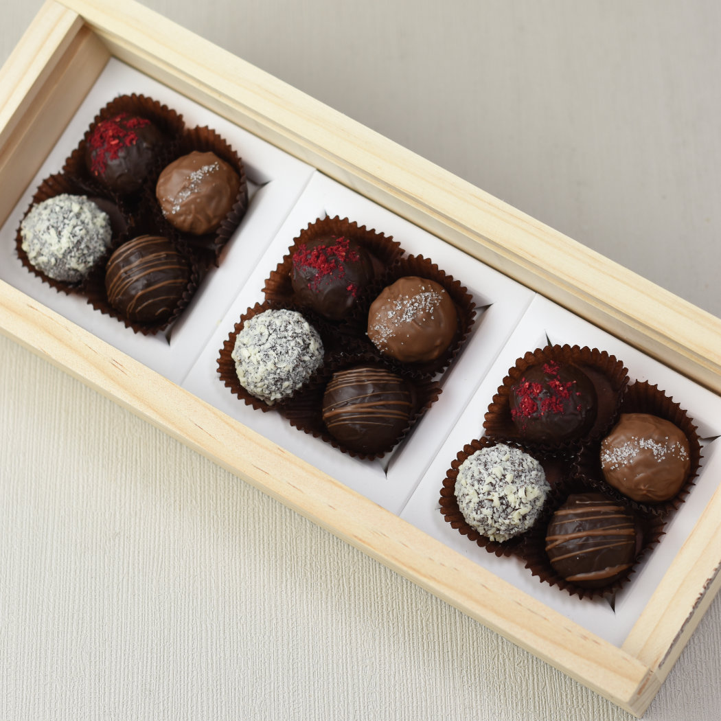 Aroha Chocolate Twelve Mixed Truffles Luxury Wooden Gift Box. Top view of an open box of chocolates, showing the beautiful hand made chocolate truffles within, three of each flavour.